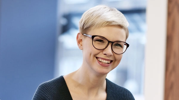 Professionelle Frau mit Brille lächelt herzlich in modernem Büro.