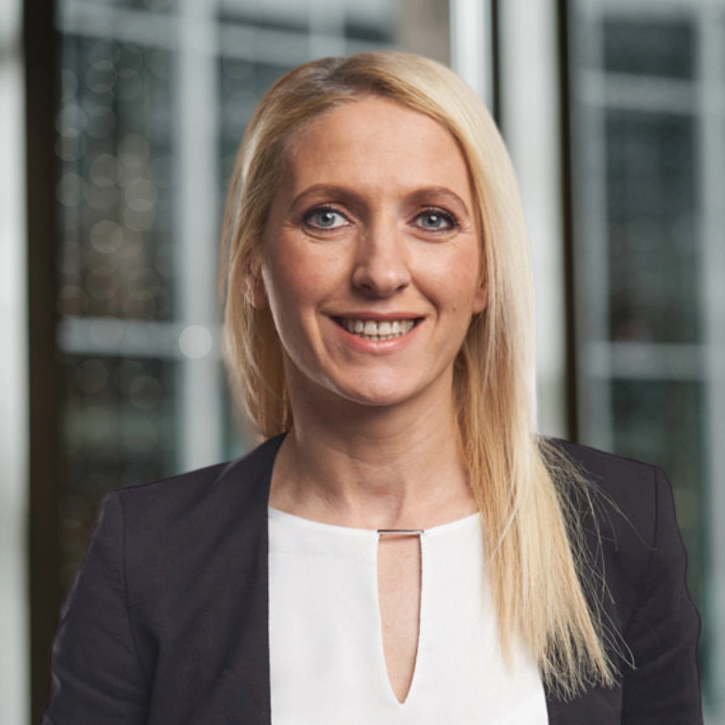 Professionelles Porträt einer lächelnden Frau in einem modernen Büro.